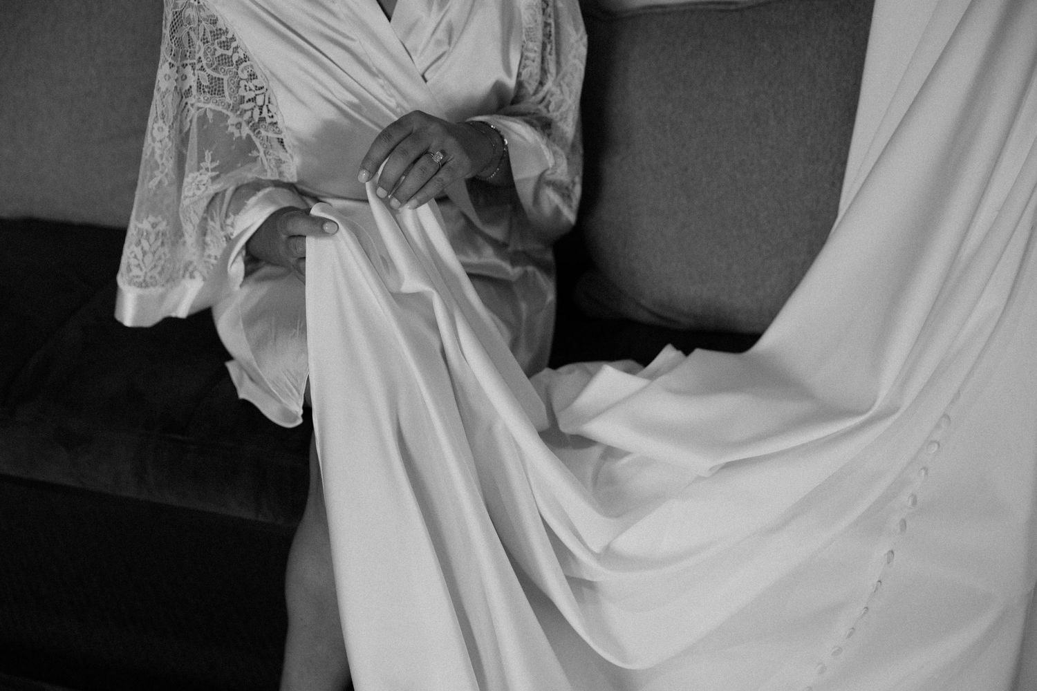 Close-up of hands adjusting the flowing fabric of a white robe or gown.