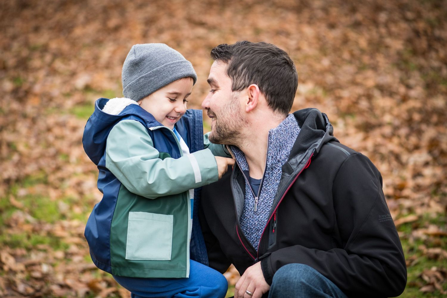 5 year old boy cuddling his dad surrounded by leaves during an Autumn photoshoot
