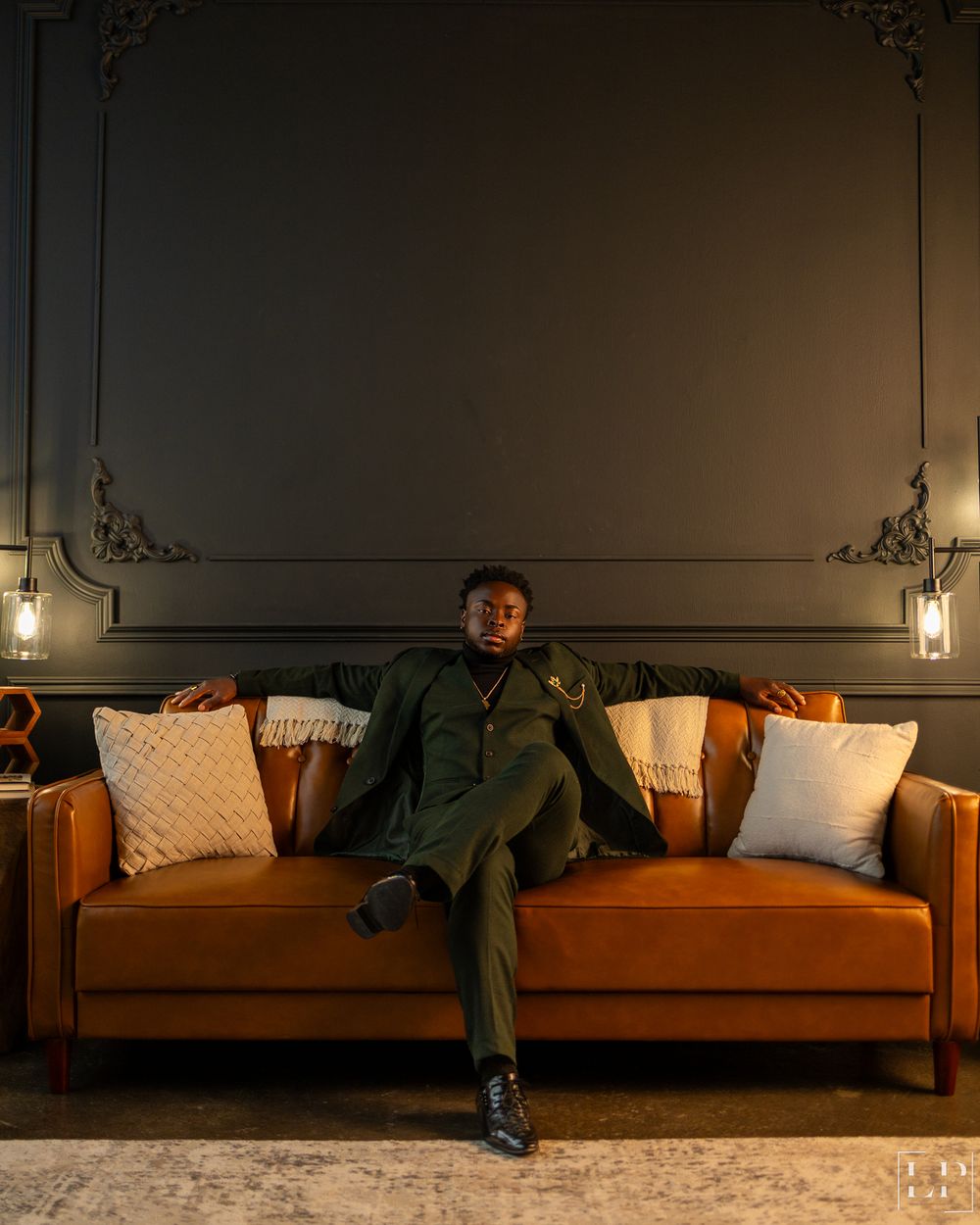 Stylish living room scene with person lounging on tan couch against dark walls.