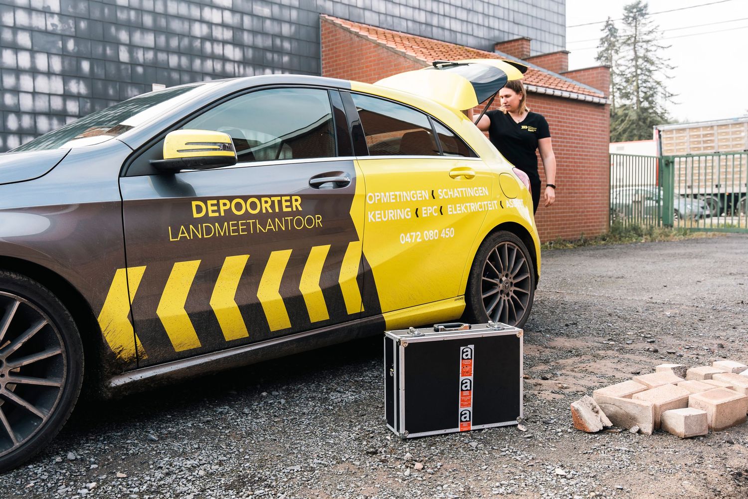 Yellow and black striped forensic investigation vehicle parked next to brick building.