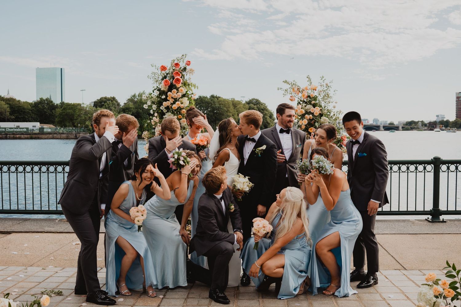 Wedding party poses together on a waterfront dock during golden hour.