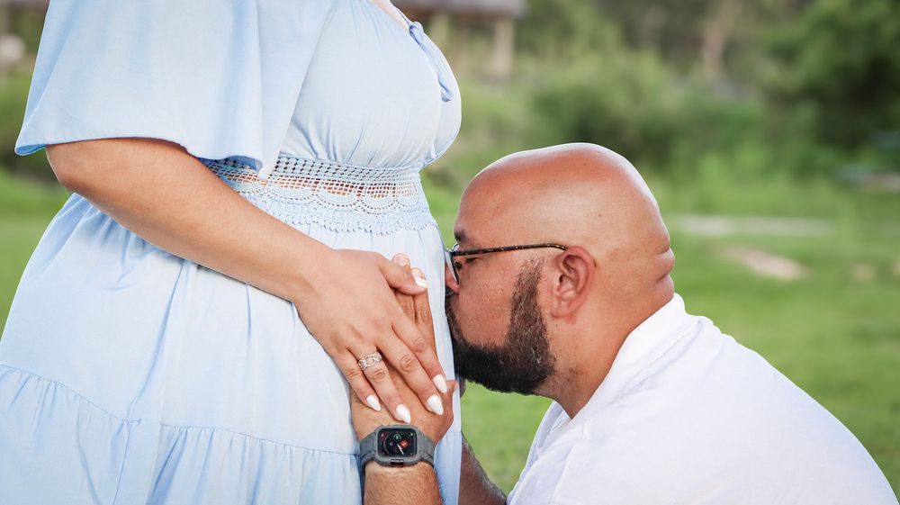 Couple in white clothing embraces during outdoor photo session.