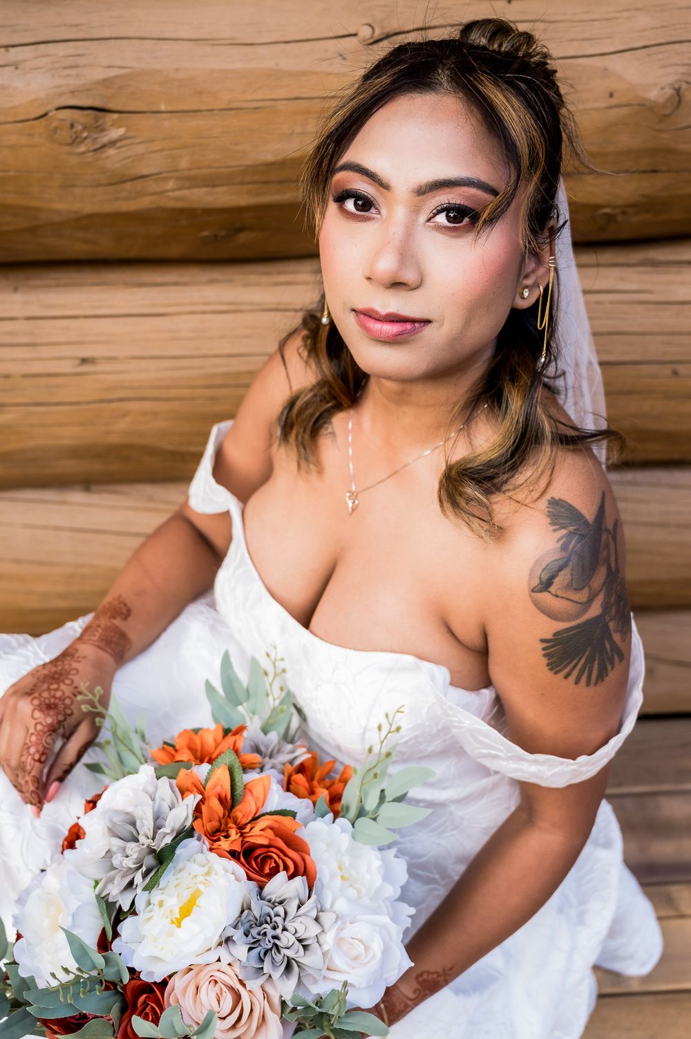 A bridal portrait series showing a white wedding dress and colorful bouquet with orange and white flowers against wood walls.
