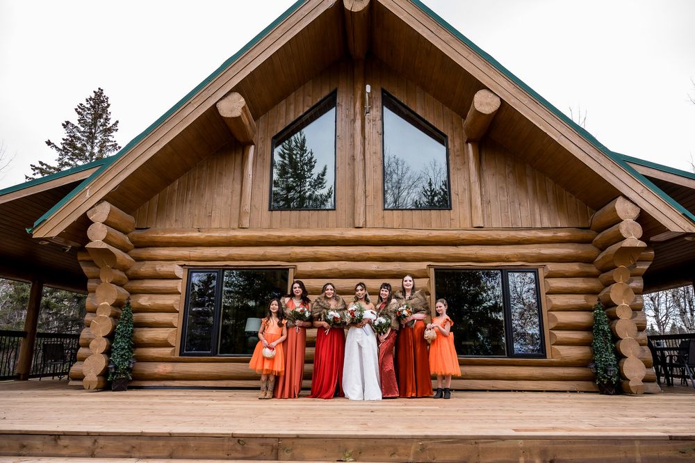 Rustic wooden lodge exterior with orange bridesmaid dresses hanging from the upper deck railing.