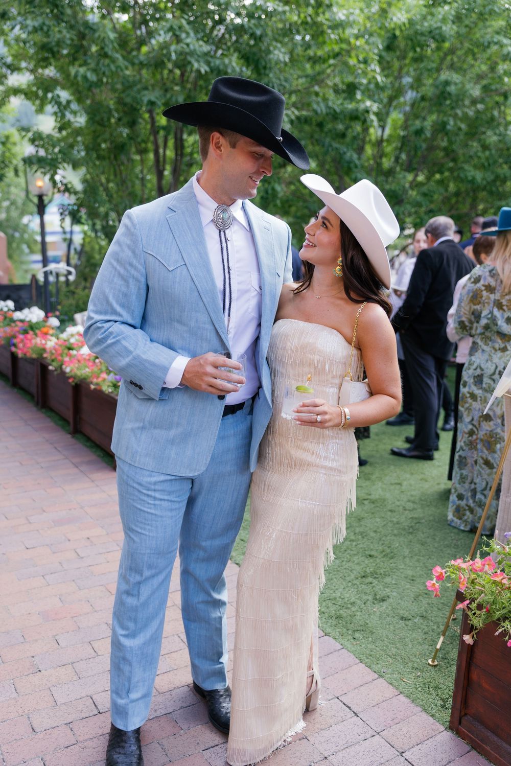 A couple in western-inspired formal wear, with a light blue suit and cowboy hat paired with a champagne evening gown. aspen vibes