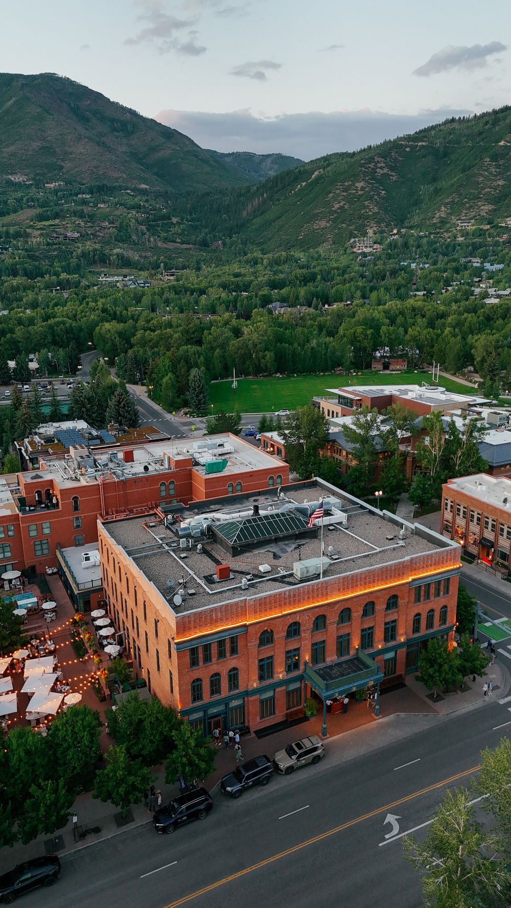 Aerial view of historic red brick buildings along Main Street in Aspen, Colorado with mountains in the background.