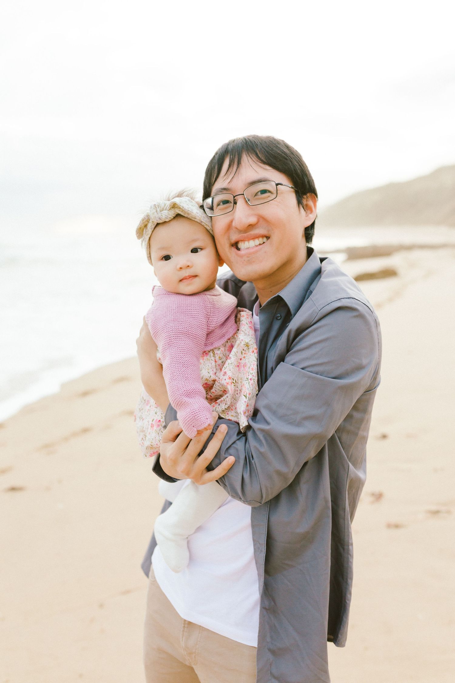 A parent and baby share a joyful moment together on a sunny beach.
