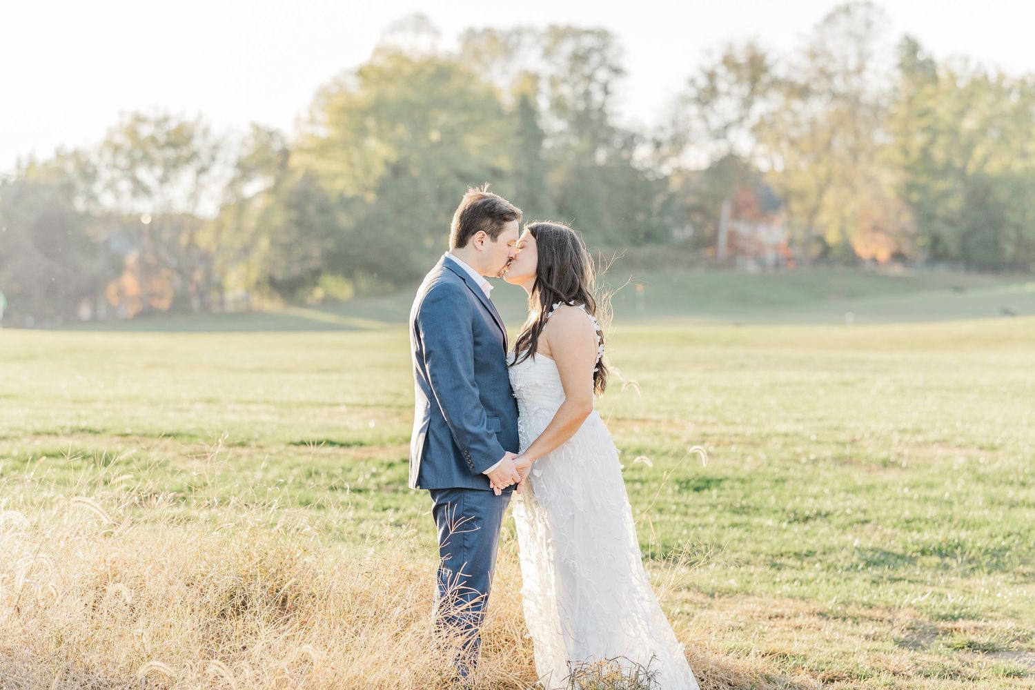 A couple shares a romantic moment in a sunlit autumn field during their wedding photo session.