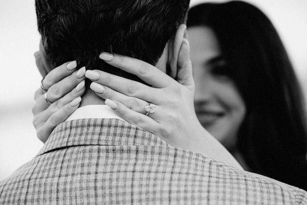 Close-up black and white photo of intimate embrace between couple.