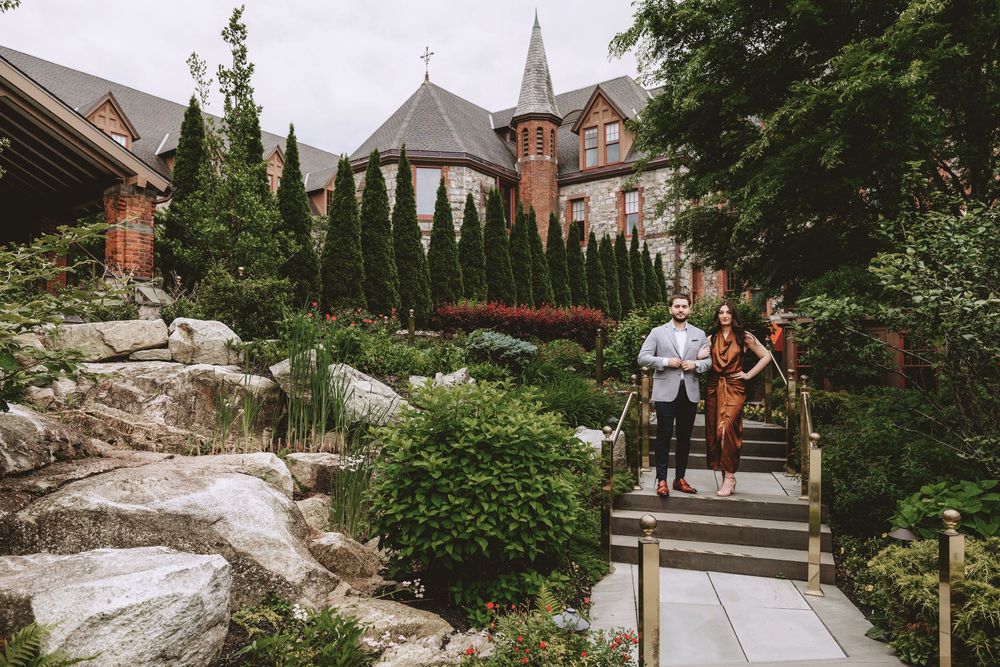 Outdoor wedding ceremony setup with stone pathways and elegant architecture in background.