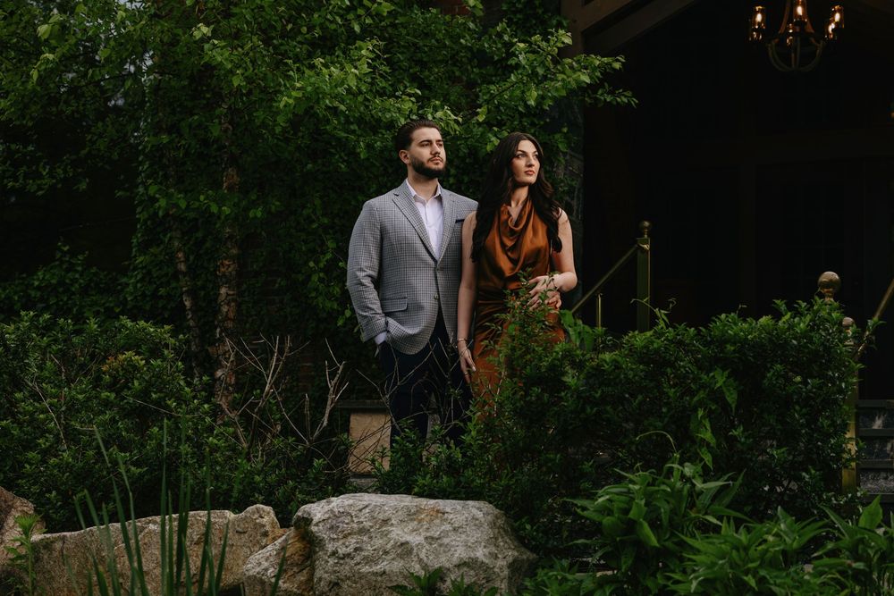 Romantic outdoor portraits of couple amid lush garden greenery at sunset.