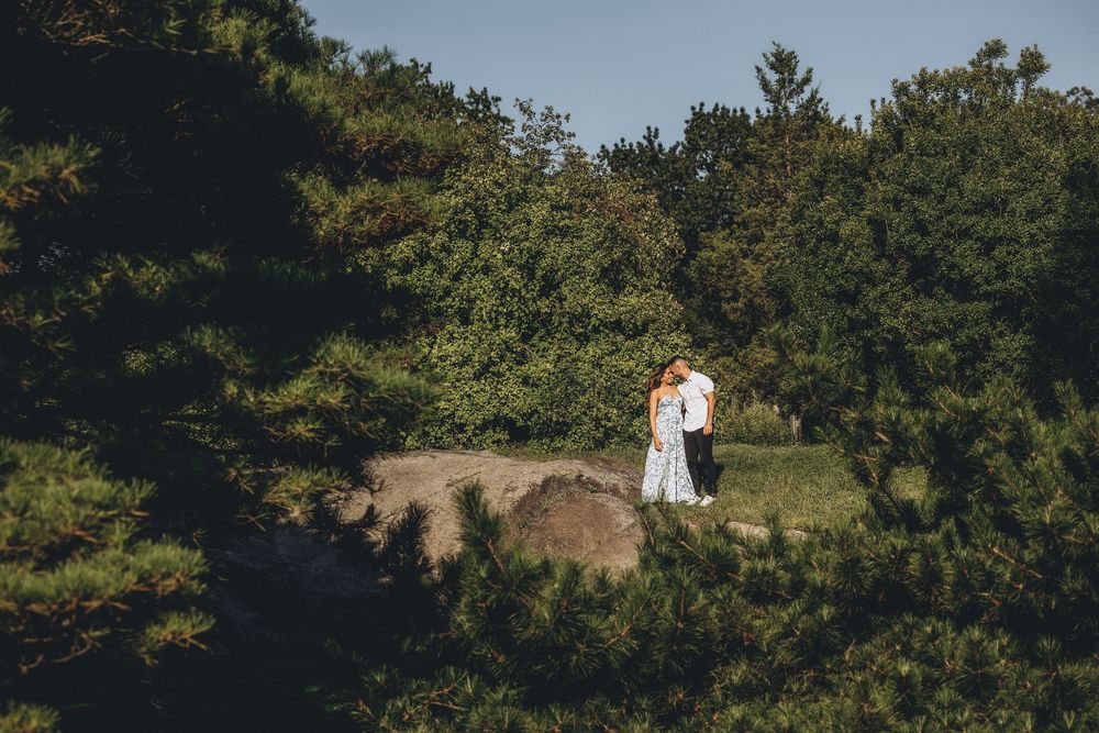 Panoramic view of a couple's photoshoot in a scenic hilltop garden.