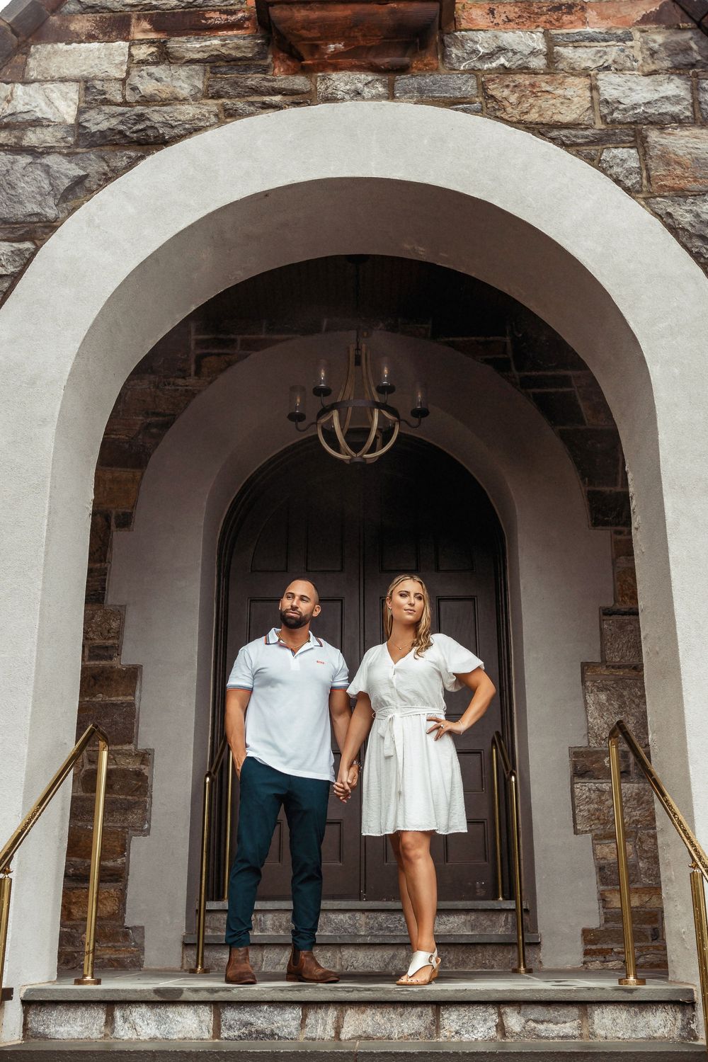 Romantic couple posing under stone archways of a rustic building.