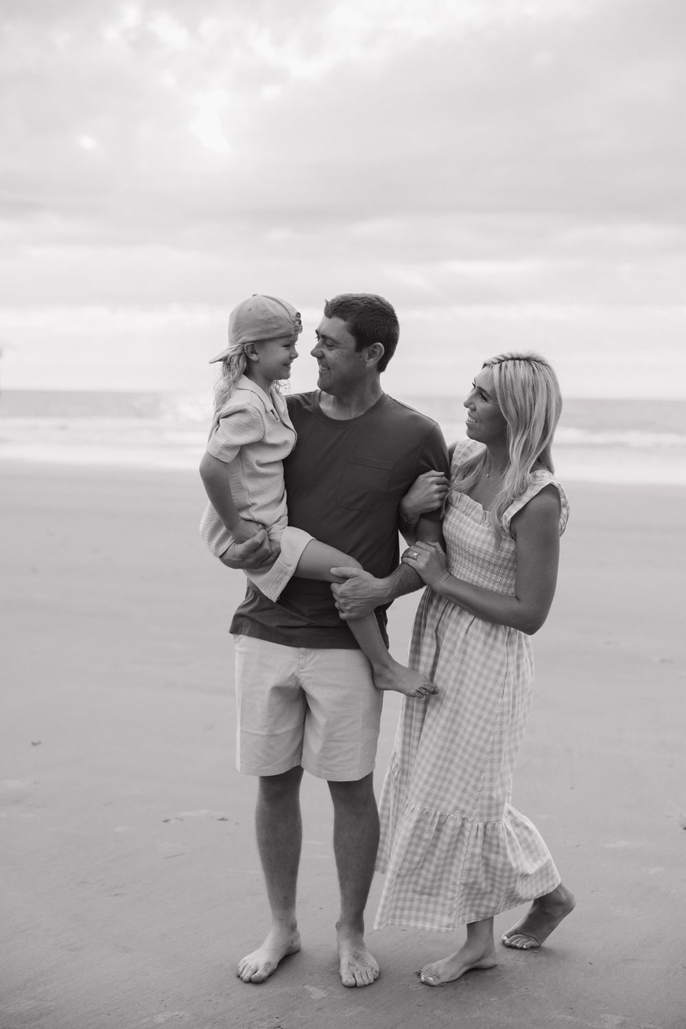 Black and white photo of a family sharing an intimate moment together on the beach.