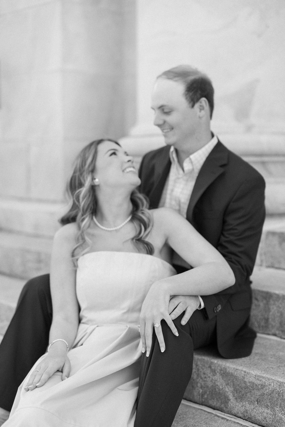 A romantic black and white portrait of a couple sitting on stone steps.