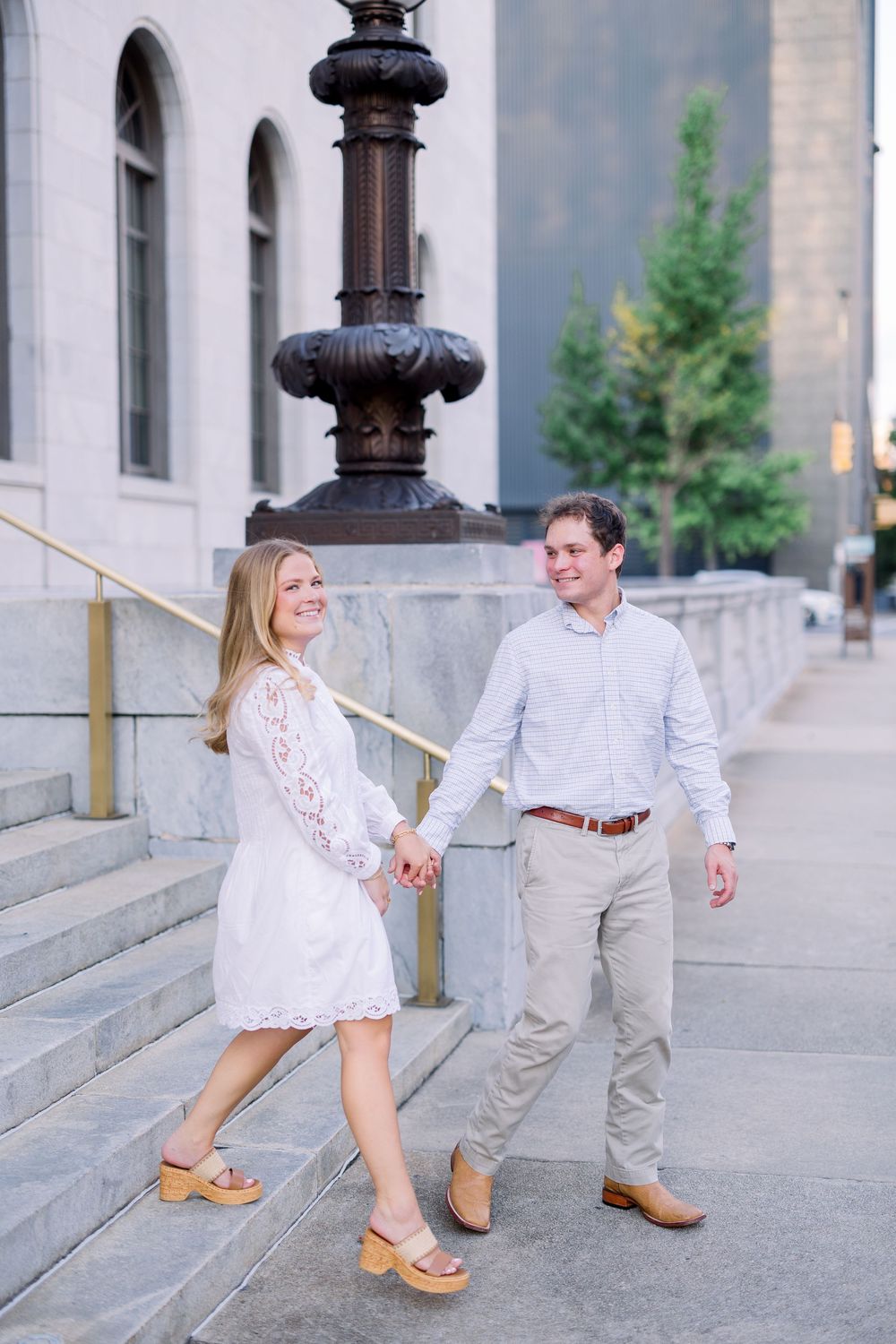 A couple dances playfully along a classical stone colonnade.