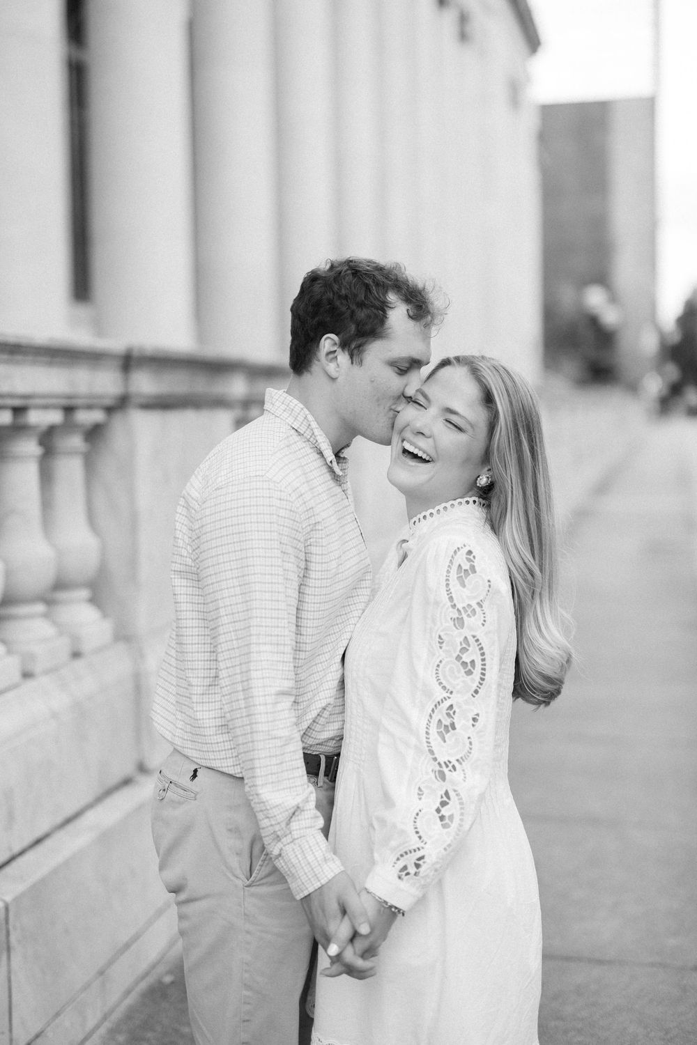 A joyful couple sharing a romantic moment in front of a classic white columned building.