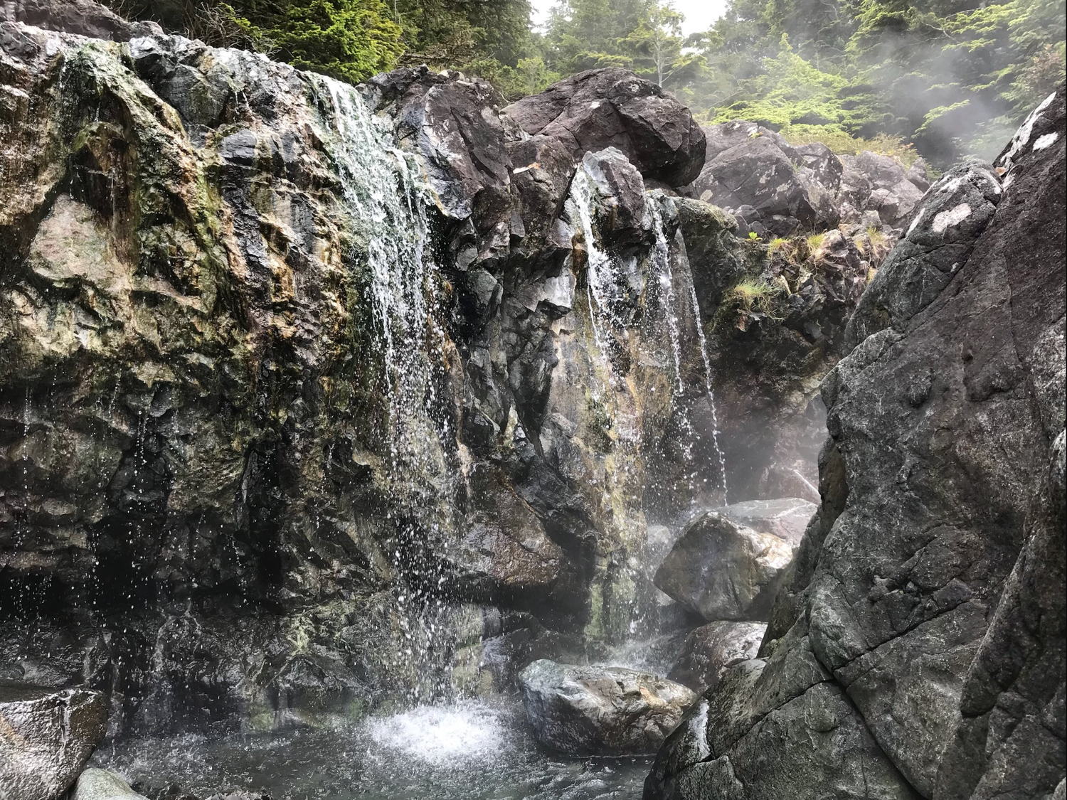 waterfall cascades over the cliff and into the natural hot springs at Hot Spring Cove in Tofino