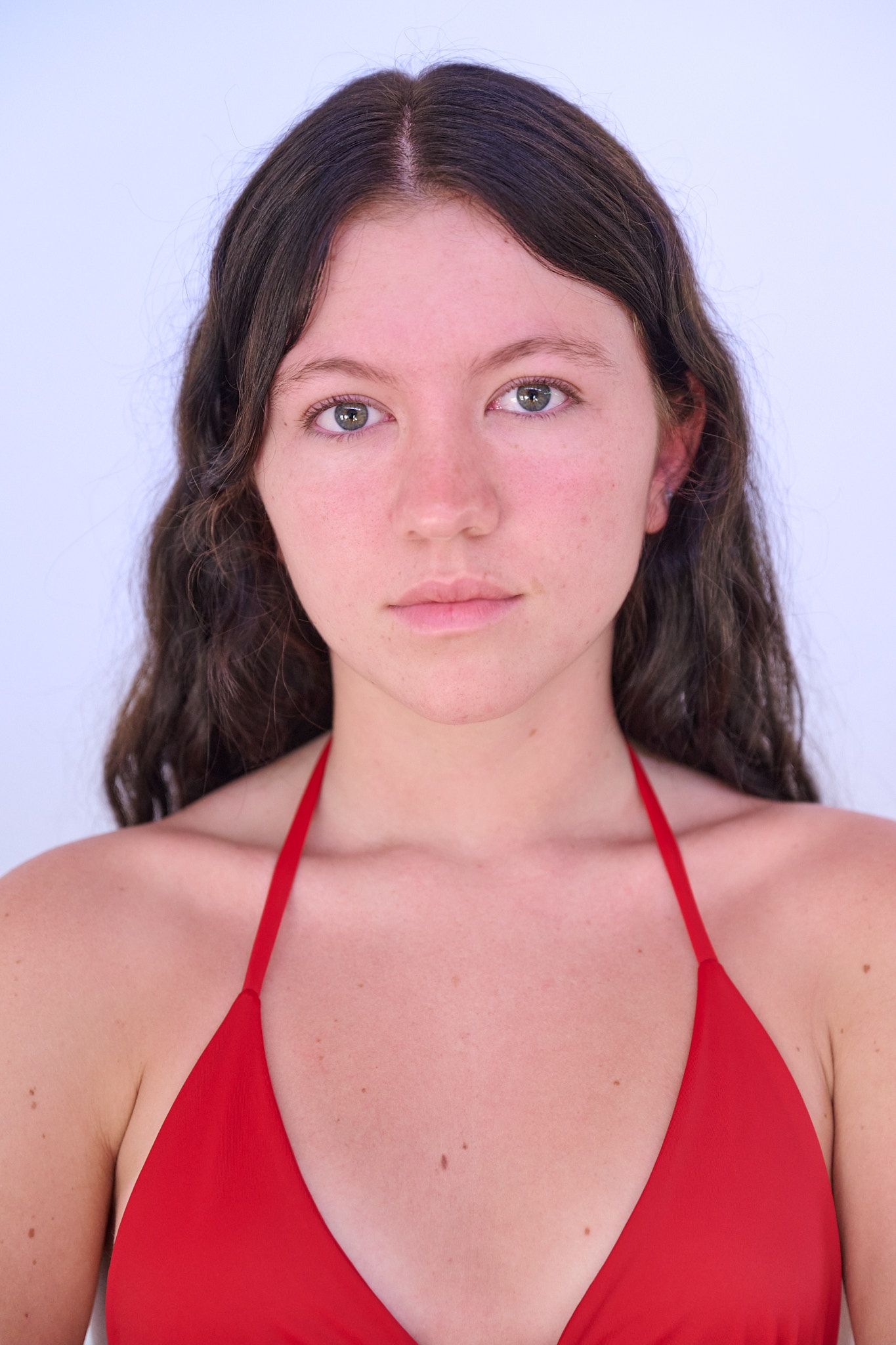 Model wearing a white crop top and light blue high-waisted jeans poses against a light blue background.