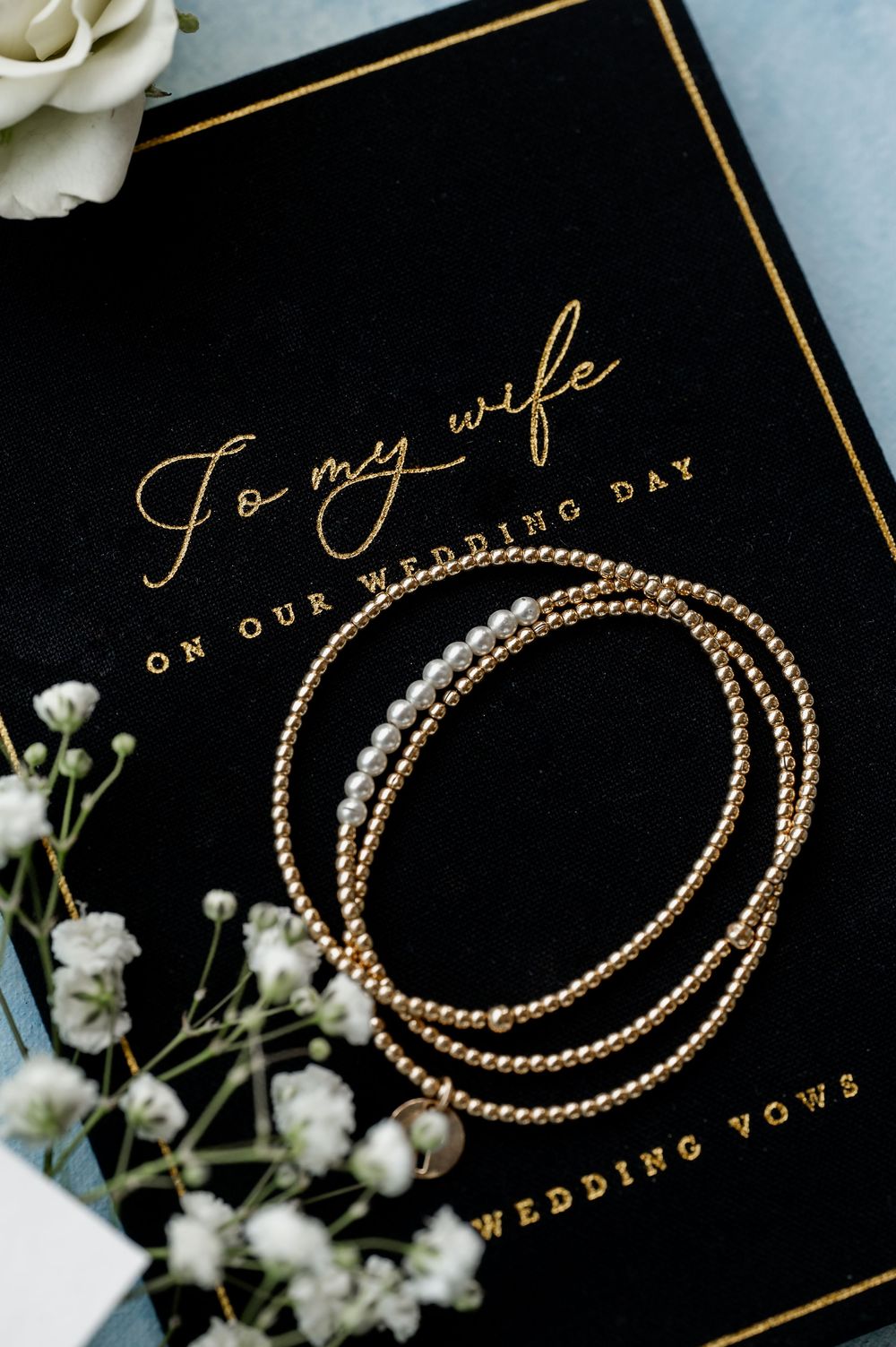 Gold wedding bands and text on black cards with white floral accents.