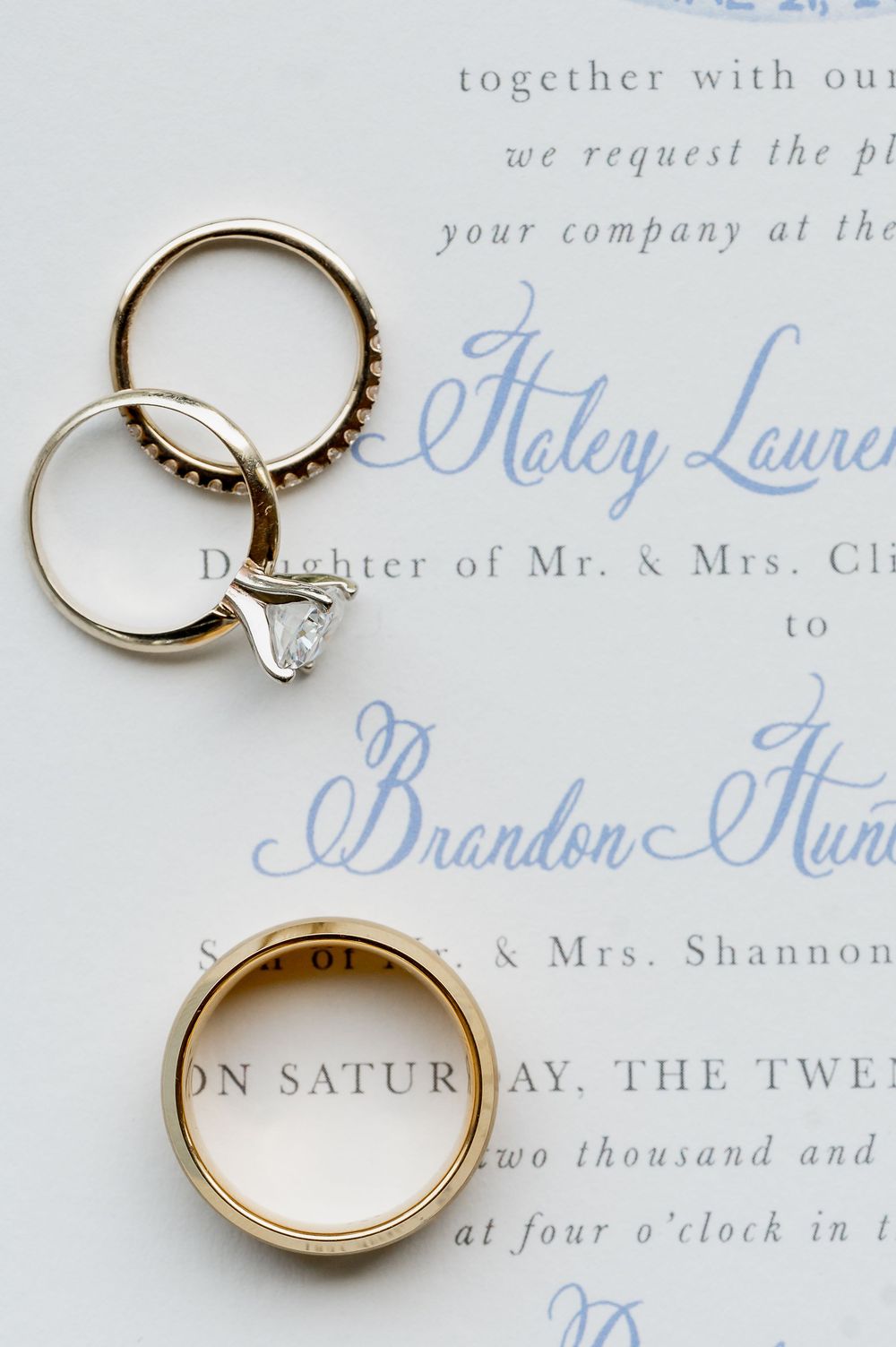Wedding rings photographed on elegant blue and white wedding invitation.
