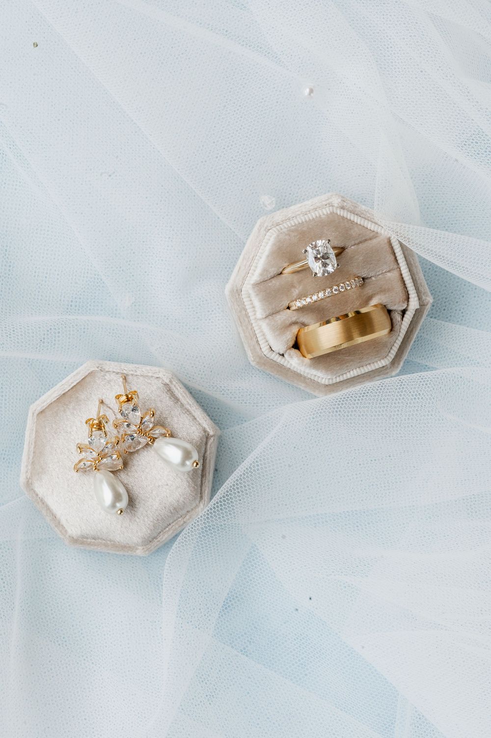 Wedding rings and jewelry displayed in elegant beige hexagonal ring boxes.