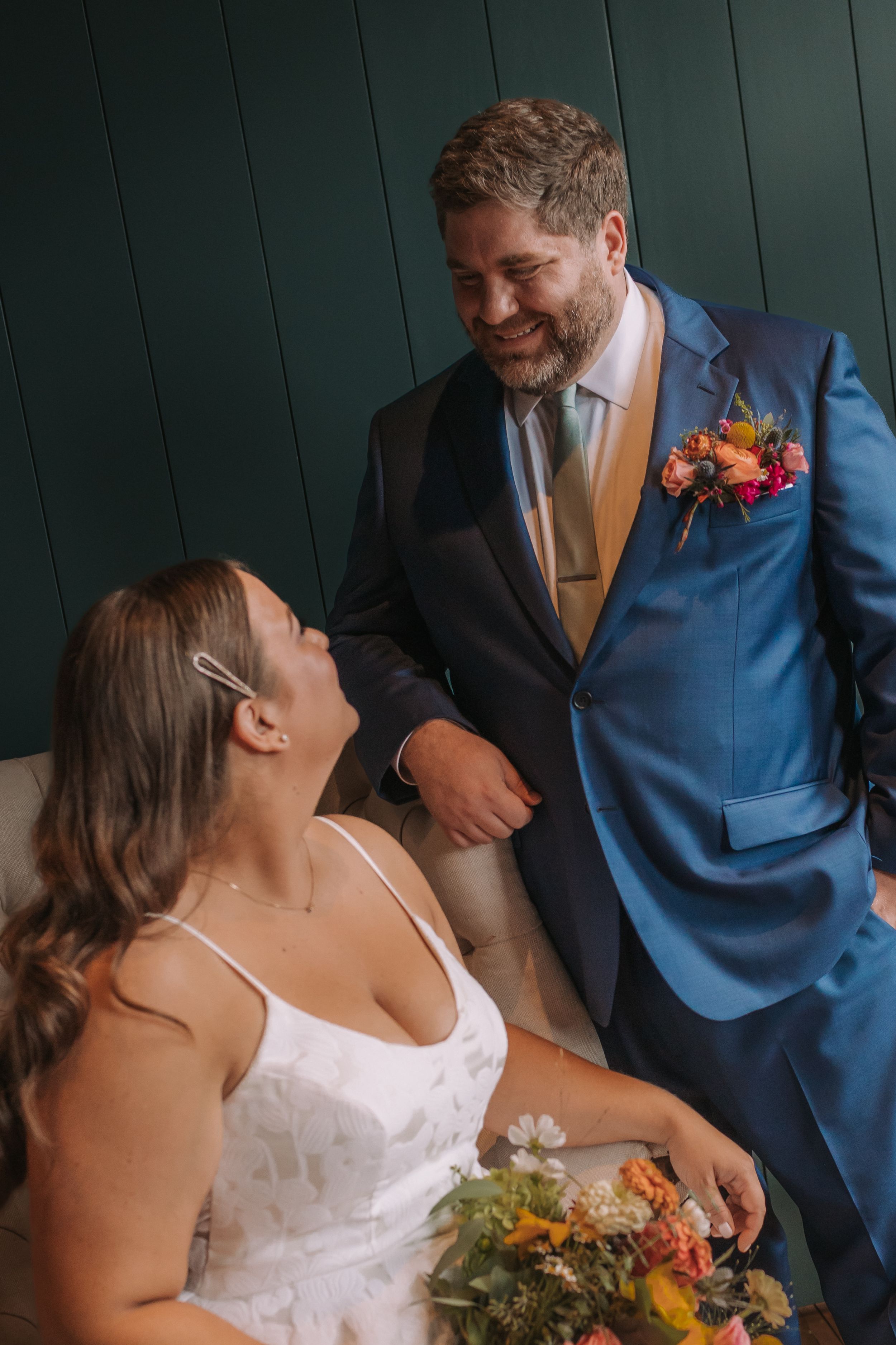 A sequence of romantic wedding moments showing a couple in a white dress and blue suit against a dark green wall.