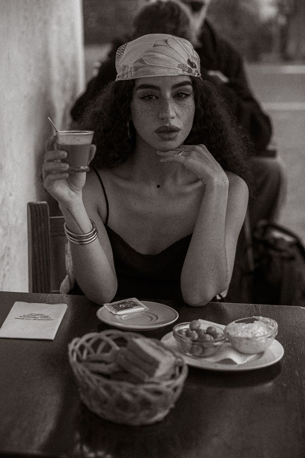 A series of black and white photos showing someone drinking coffee and enjoying a meal at a cafe table.