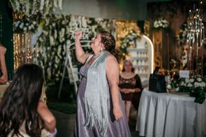 Person in silver fringe dress dances at a festive event with hanging lights.