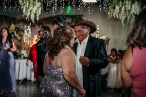 Guests dance together during evening celebration under hanging lights.
