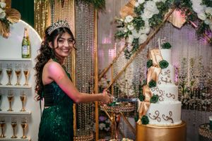 A guest in emerald dress prepares to cut an elegant tiered white cake at a celebration.