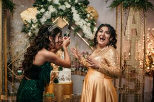 Two guests share an excited moment at a celebration with decorated backdrop.