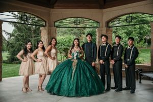 Wedding party poses under gazebo with bridesmaids in beige and groomsmen in black around quinceañera dress in emerald green.