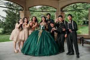 Celebratory group photo under gazebo with emerald ball gown and coordinating formal attire.