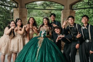 Fun group photo under gazebo with formal party in emerald green and beige attire.
