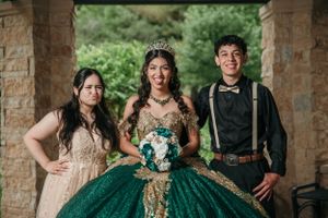 Formal celebration photo under stone archway with emerald green ballgown as centerpiece.
