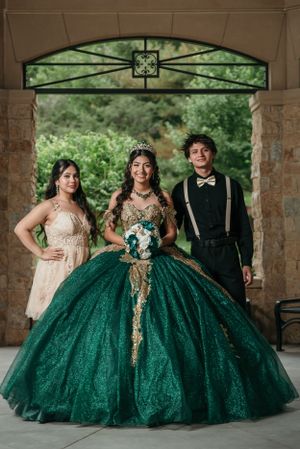 Formal group photo under decorated stone archway featuring emerald green ballgown.