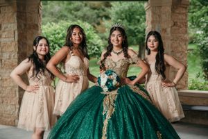 Quinceañera celebration group photo with matching formal attire in emerald and blush tones.