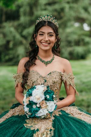 Elegant emerald green and gold quinceañera dress with matching crown and jewelry.