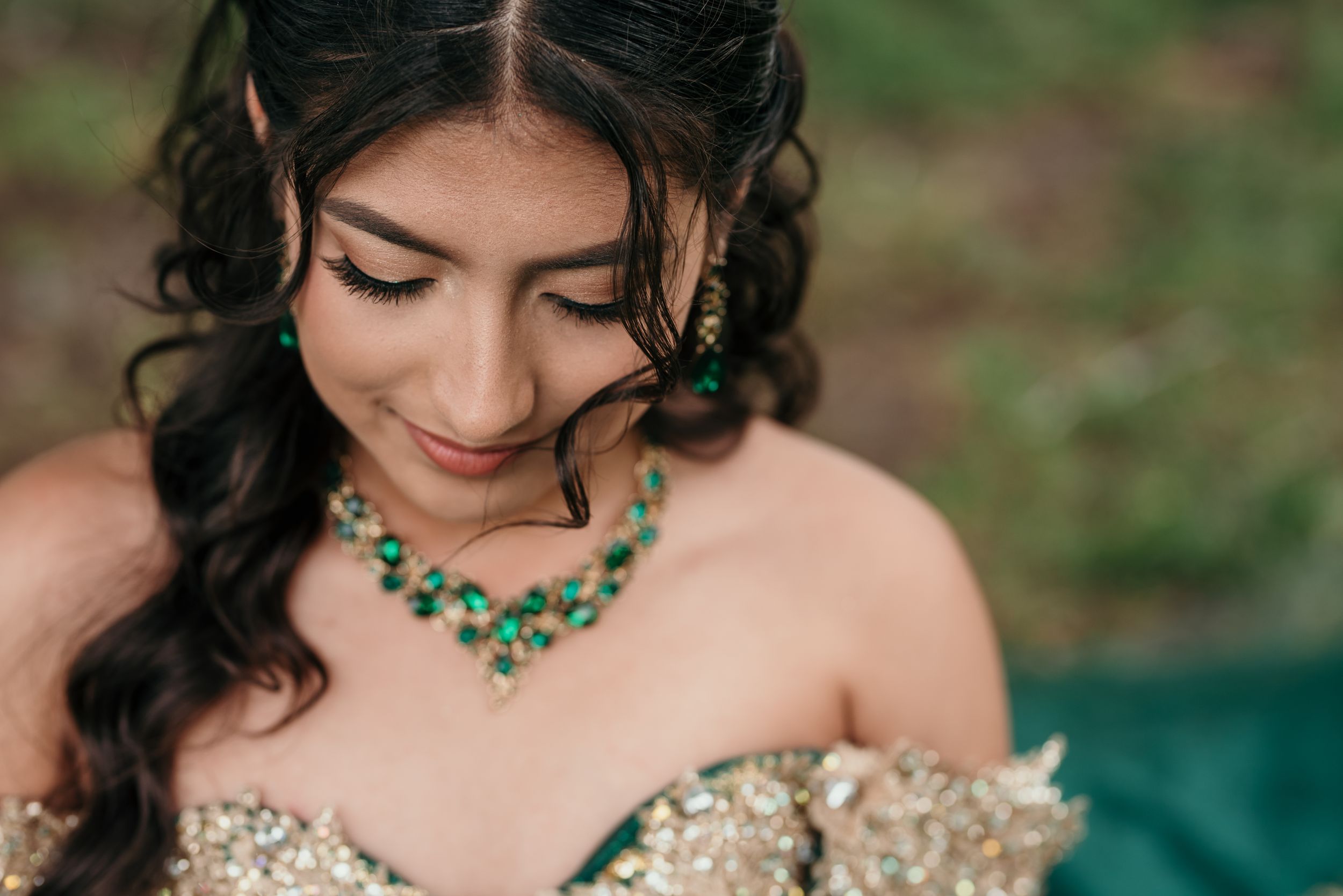 Intricate emerald jewelry and gold embellishments adorn a formal dress.