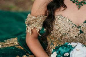 Close-up of gold sequined bodice with emerald green details on formal gown.