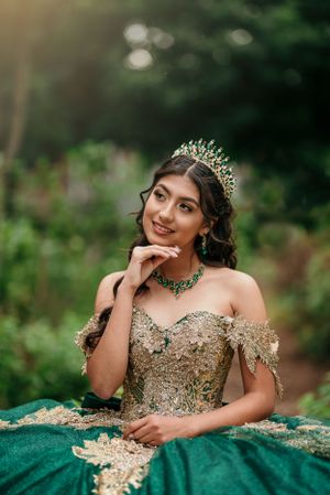 A formal portrait featuring an emerald green and gold gown with matching crown and jewelry.