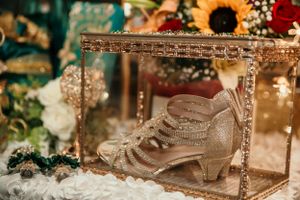 Vintage lace boot displayed in an ornate glass case with flowers and holiday decorations.