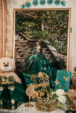 Quinceañera display featuring emerald green gown photo and decorative party accessories.