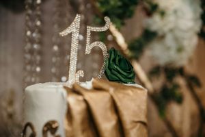Close-up of crystal number 15 cake topper with emerald green rose decoration.
