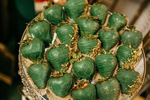 Decorative green chocolate covered strawberries arranged on an elegant silver platter.