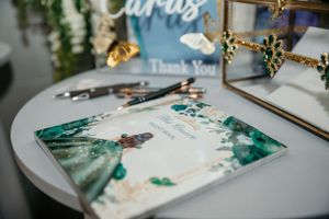 Emerald green watercolor wedding cards and stationery on white table.
