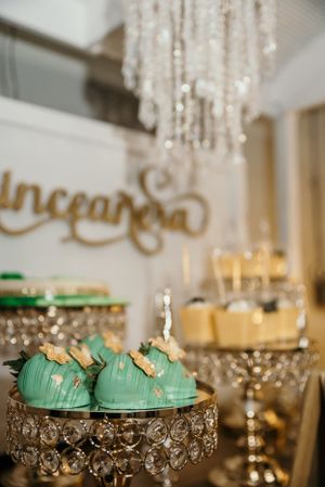 Mint green desserts displayed on crystal cake stands under elegant chandelier lighting.