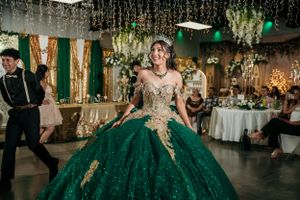 A stunning emerald green ball gown with gold accents sparkles on the dance floor.