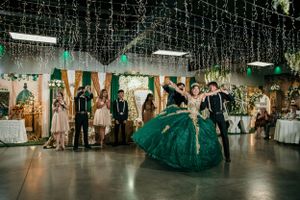 Dancing celebration in an elegant venue decorated with hanging lights and emerald green decor.